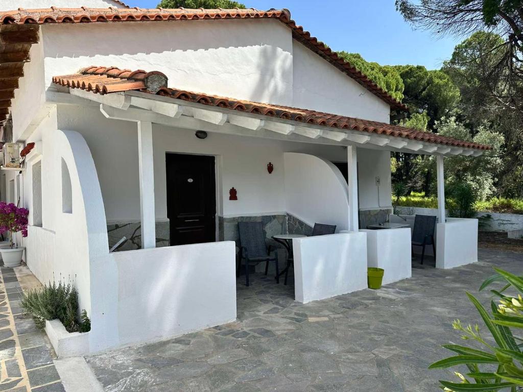 Villa Nikos Koukounaries في كوكونارييس: بيت ابيض امامه طاوله