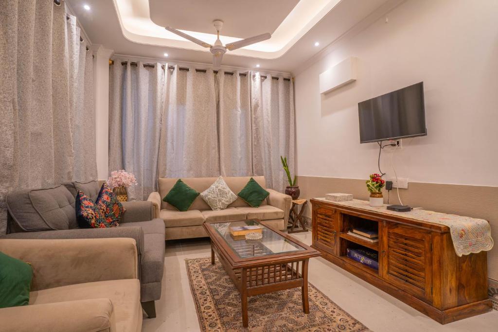- un salon avec un canapé et une télévision dans l'établissement Hostie TJH - Cute Mini 2BHK apt, Saket, near Max Hospital, à New Delhi