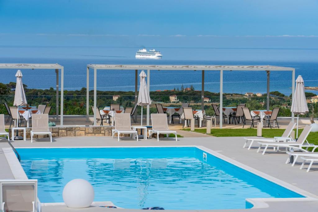 una piscina con sillas y un crucero al fondo en Drita Studios & Apartments, en Svoronata