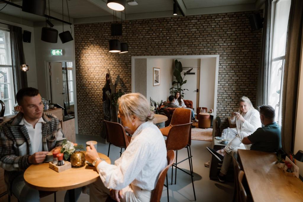 Stadsklooster Dordt Hotel&Hostel في دوردريشت: مجموعة من الناس يجلسون على الطاولات في المطعم