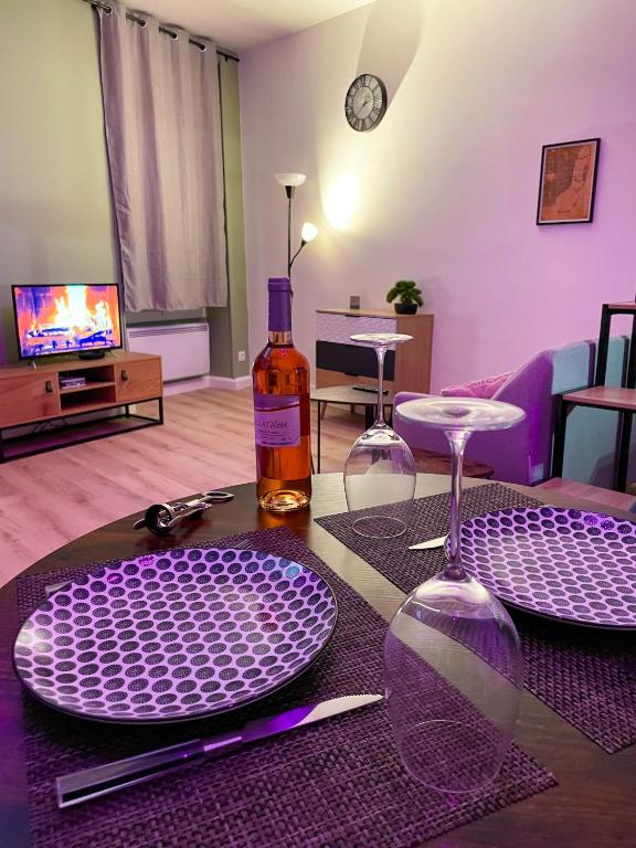 une table avec deux assiettes violettes et une bouteille de vin dans l'établissement Escapade Ardéchoise - Parking Gratuit - Château à 2 pas, à Aubenas