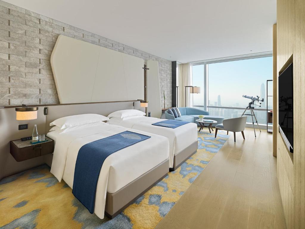 a hotel room with two beds and a living room at Mandarin Oriental, Shenzhen in Shenzhen