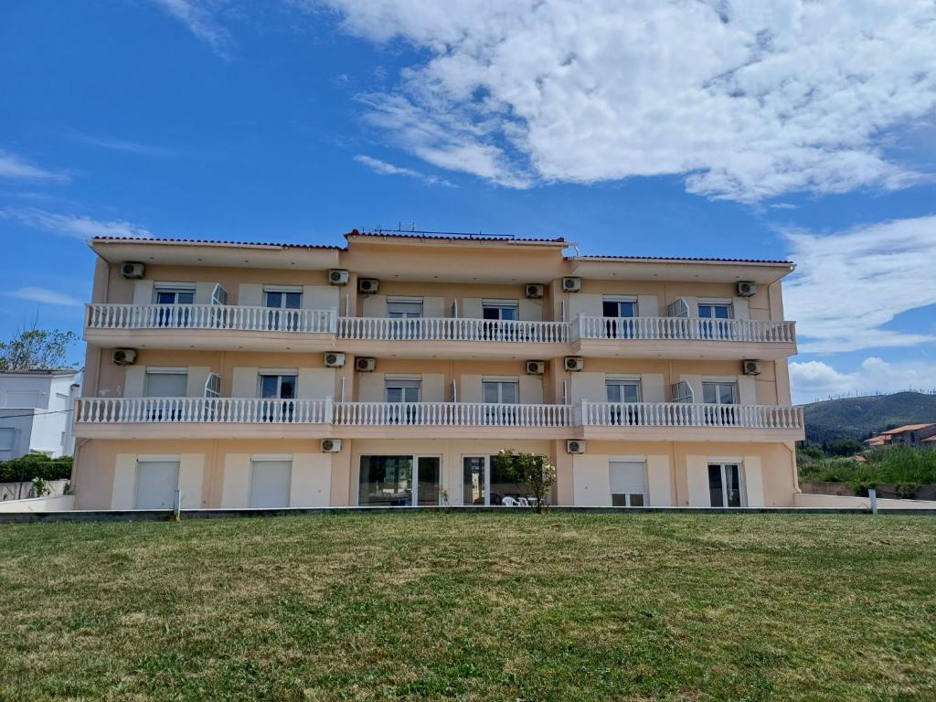 a large building with a balcony on top of a field at Aktaion apartments in Artemísion