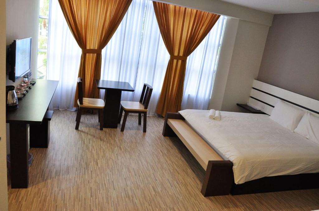 a bedroom with a bed and a desk and a table at Grand Kapar Hotel Kuala Selangor in Kuala Selangor