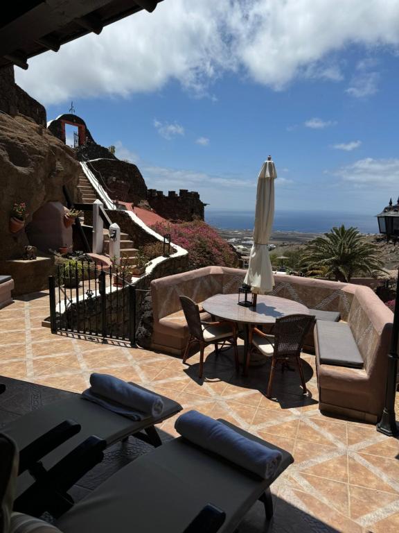 een patio met banken en een tafel met een parasol bij Castillo Lanzarote Villa 1 - Sleep in a Volcanic Cave in Tías