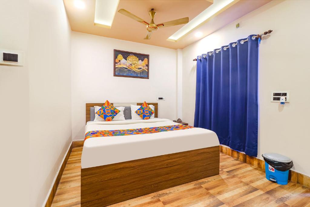 um quarto com uma cama grande e cortinas azuis em FabHotel Roadside Inn em Naksalbāri