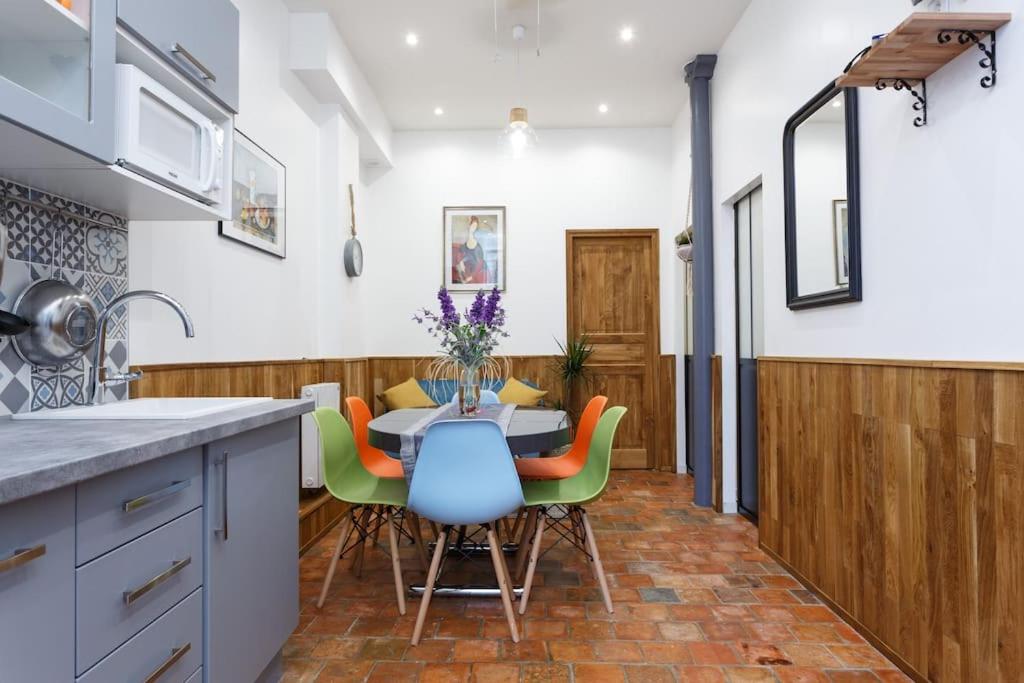 une cuisine avec une table avec des chaises colorées et une table dans l'établissement Île St Louis-Bastille-3BRD-Paris 4è, à Paris