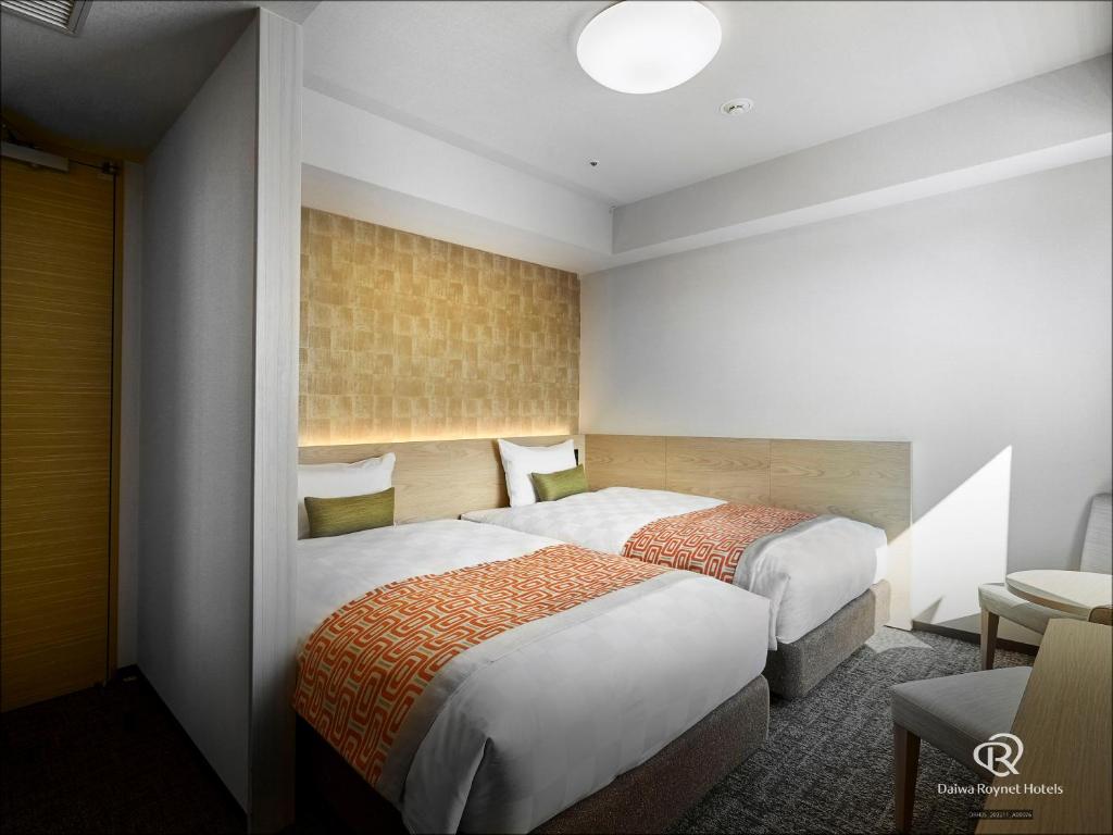ein Hotelzimmer mit 2 Betten und einem Tisch in der Unterkunft Daiwa Roynet Hotel Osaka-Uehonmachi in Osaka