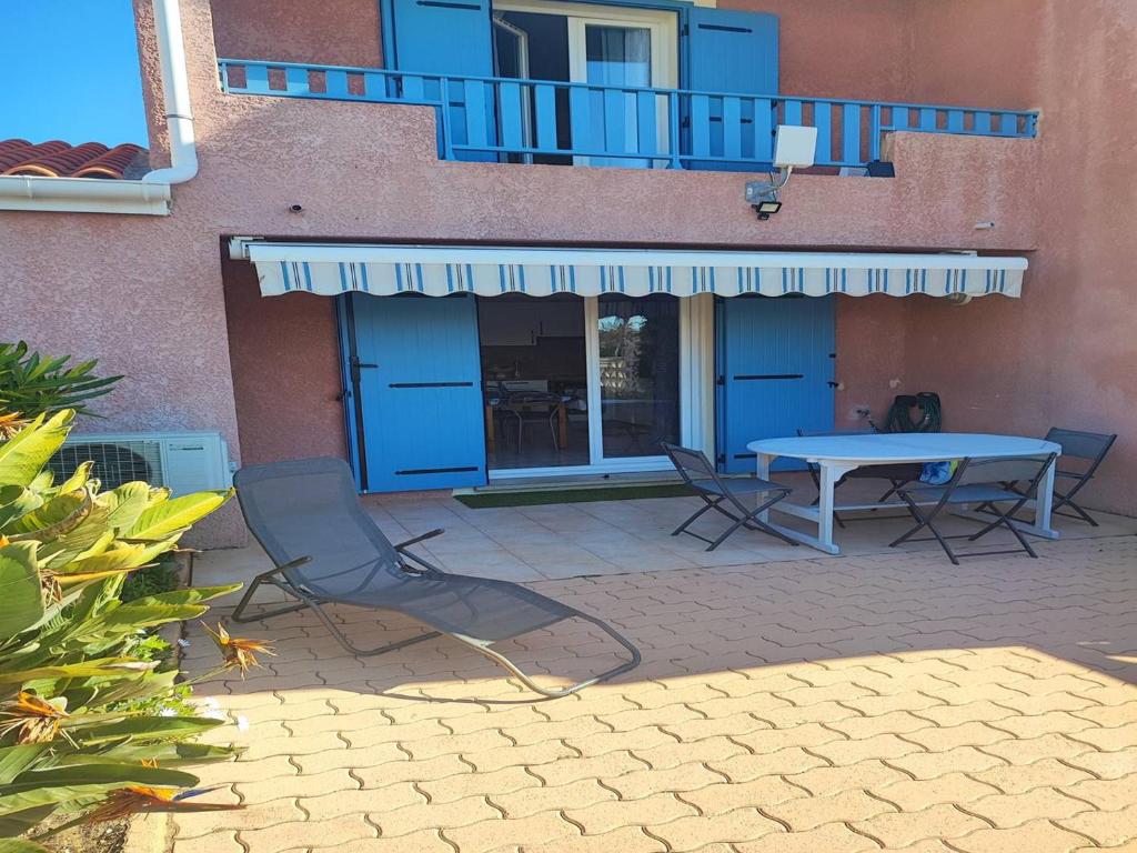 un patio avec une table et des chaises devant un bâtiment dans l'établissement Villa climatisée avec piscine et jardin à 300m des marchés et commerces, proche plage. - FR-1-782-56, au Barcarès