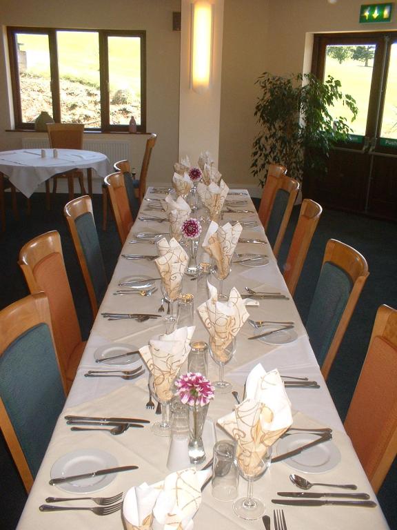 a long table with silverware and flowers on it at Bowood Park Hotel in Camelford