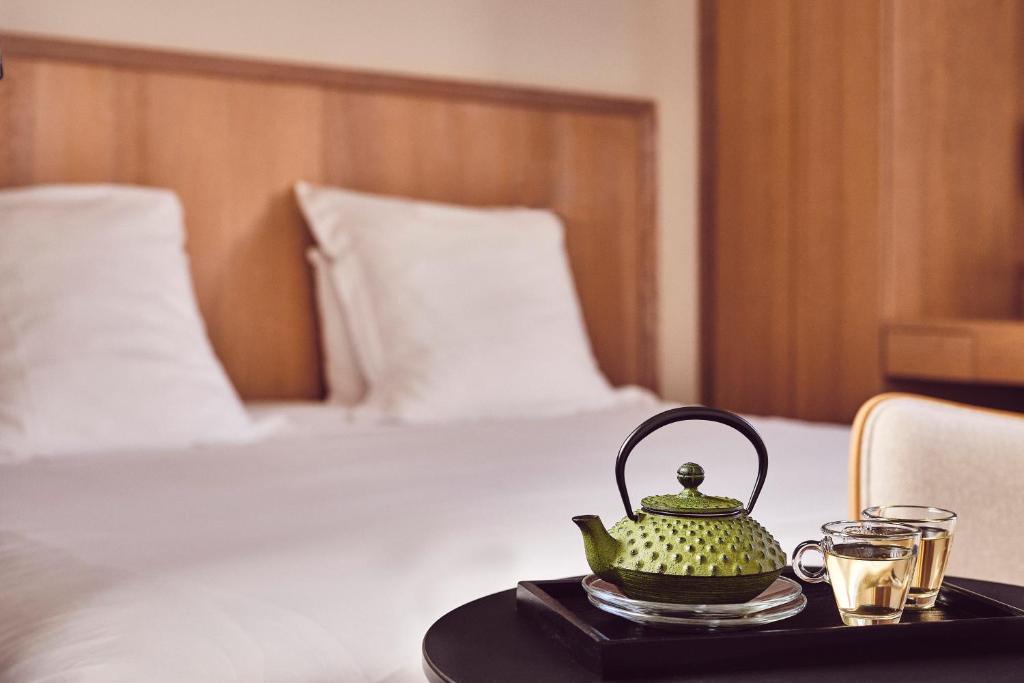 a tea kettle and two glasses on a table next to a bed at Chambres Breizh Café in Cancale