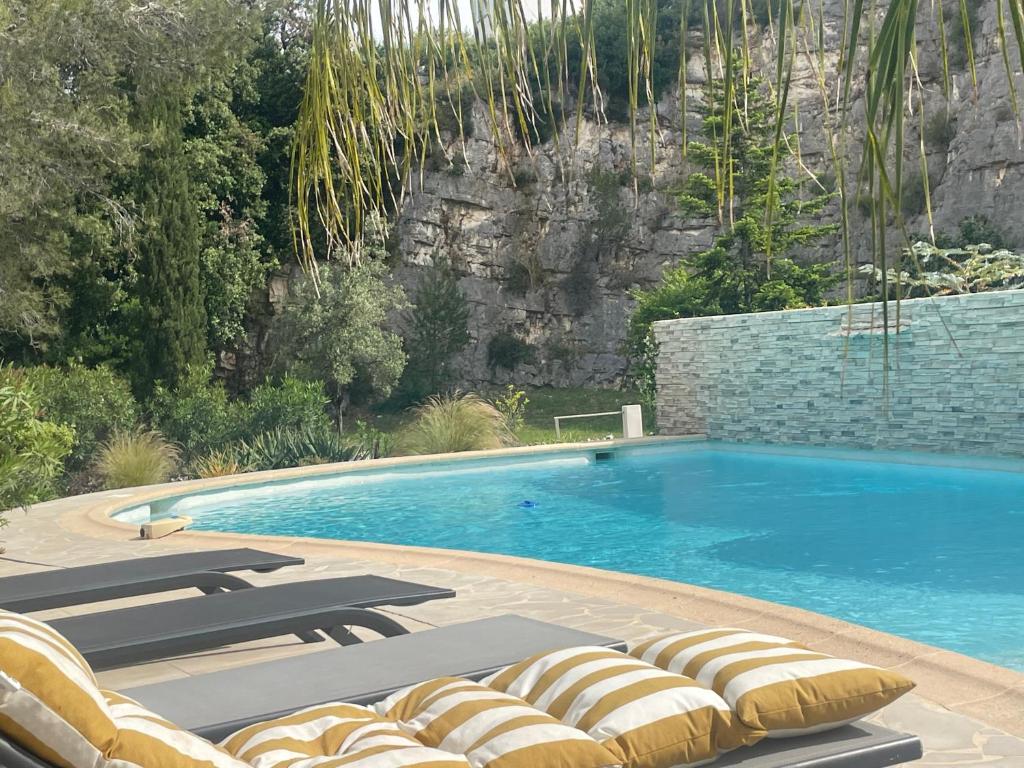 a swimming pool with lounge chairs next to a mountain at La villa des Carriers- maison avec piscine proche mer in Roquefort-les-Pins