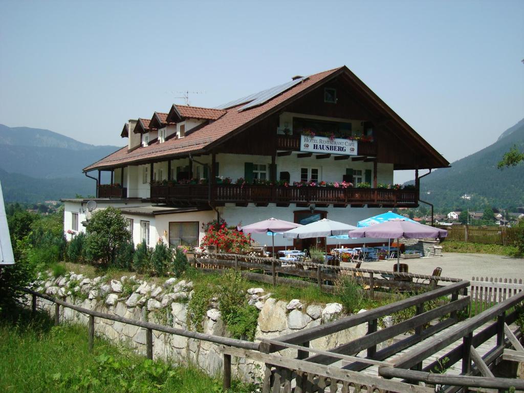 a building with tables and umbrellas in front of it at Hotel Restaurant Hausberg Garmisch-Partenkirchen in Garmisch-Partenkirchen