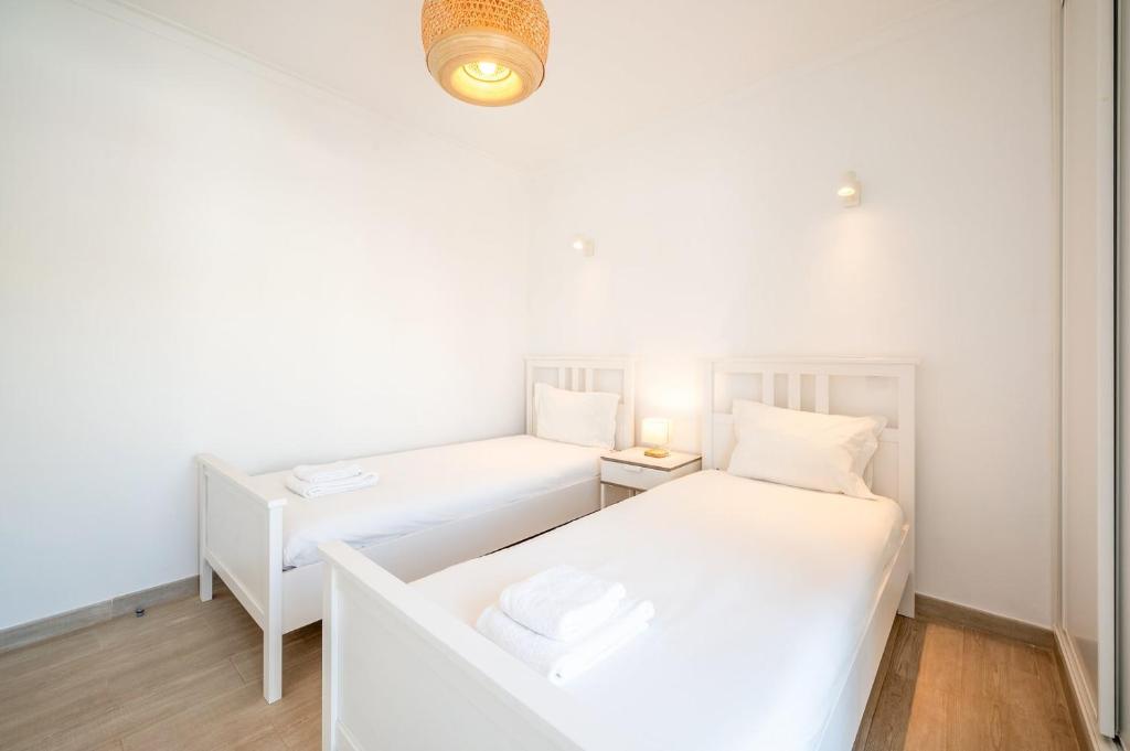 a small bedroom with two beds and a lamp at GuestReady - Sunny Retreat in Costa da Caparica in Costa da Caparica