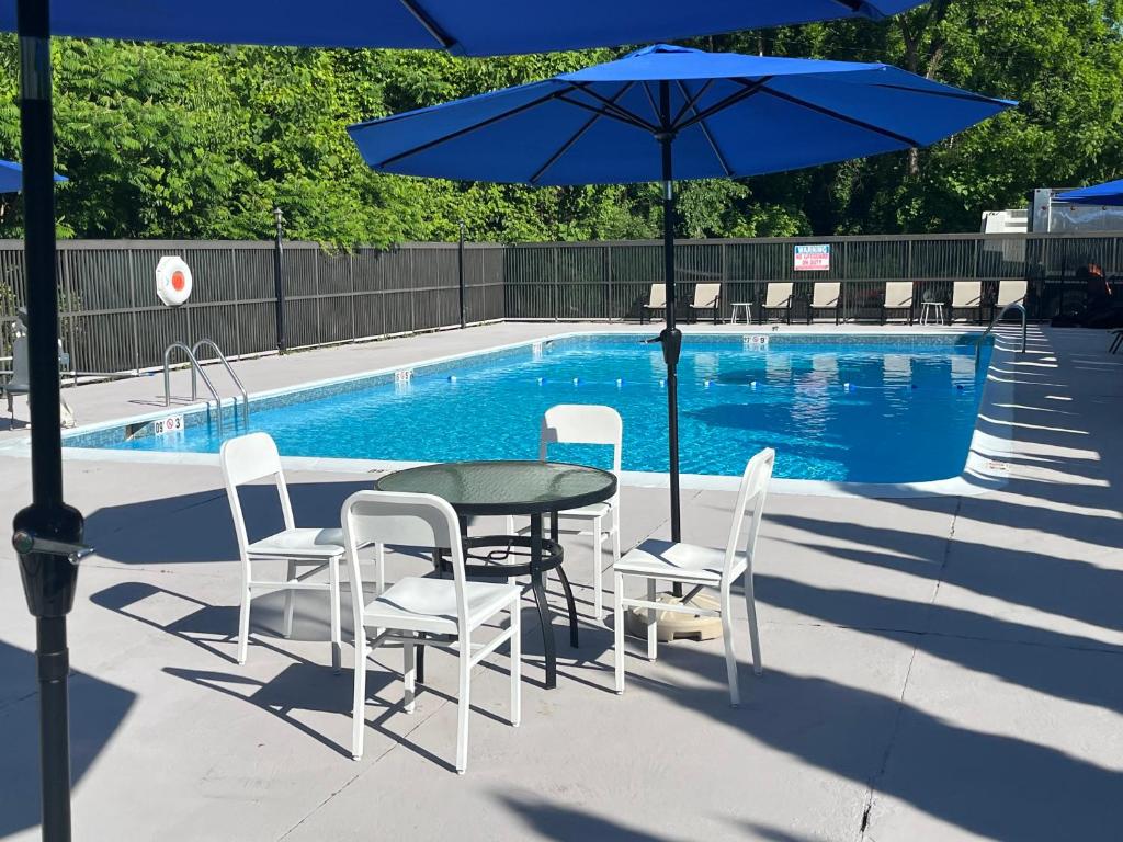 uma mesa e cadeiras com um guarda-sol ao lado de uma piscina em Comfort Inn & Suites Danbury-Bethel em Danbury