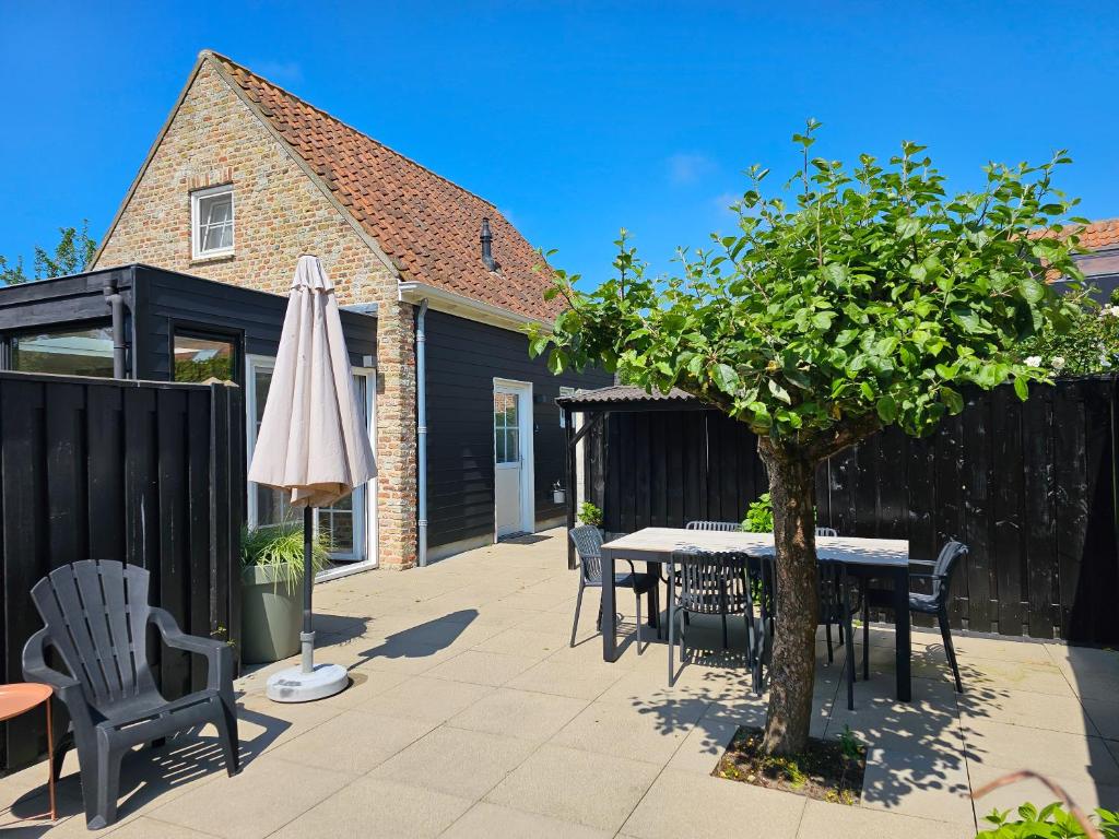 eine Terrasse mit einem Tisch, Stühlen und einem Sonnenschirm in der Unterkunft Vrijstaand vakantiehuis AK14 Aagtekerke in Aagtekerke