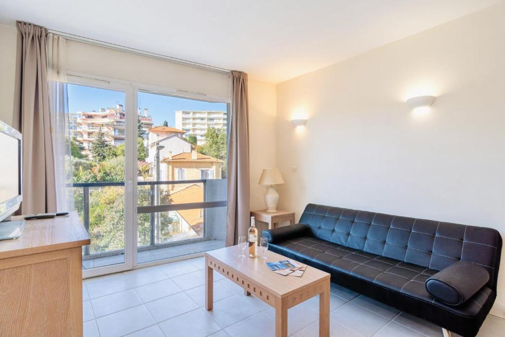 un salon avec un canapé et une grande fenêtre dans l'établissement L'Excel Canne's - 3 pièces Cannes, à Cannes