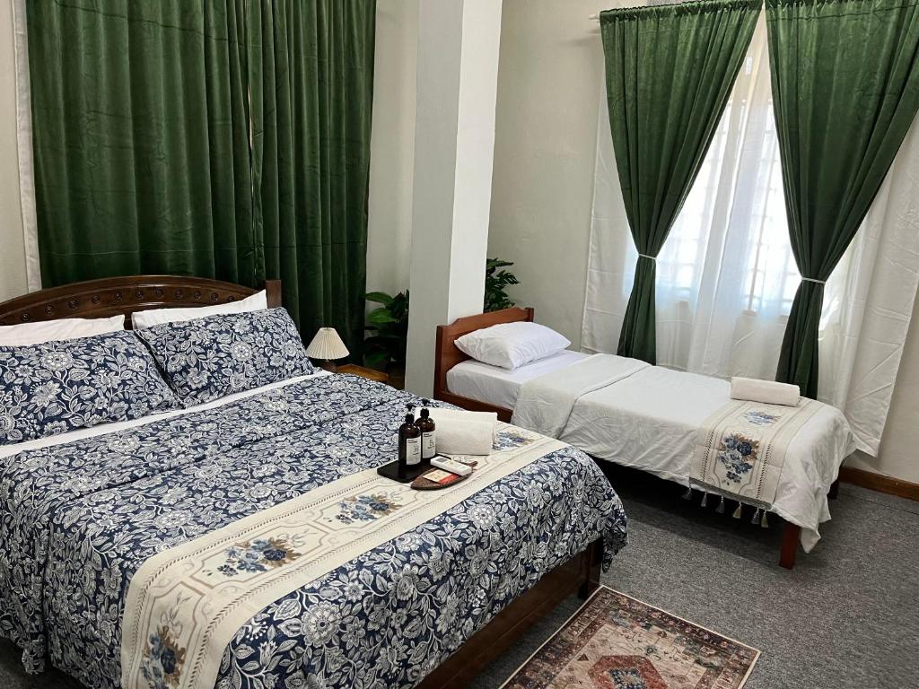a bedroom with two beds and green drapes at La Wood Homestay near Kuala Besut Jetty in Kuala Besut