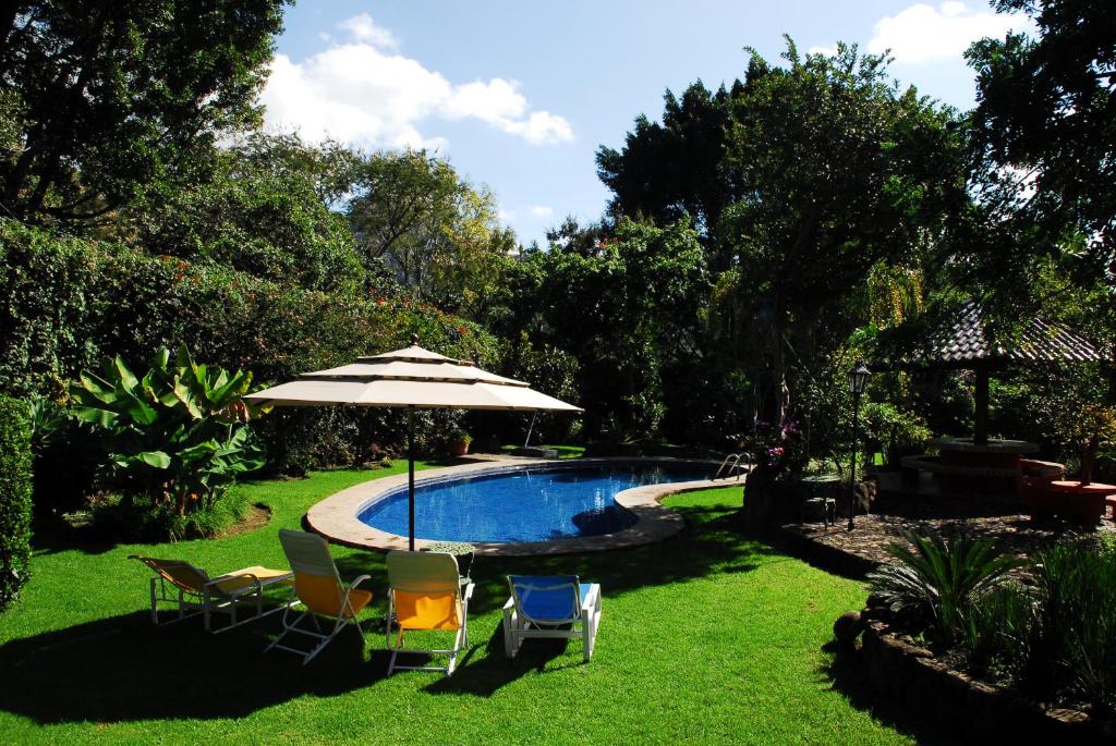 a yard with a pool with chairs and an umbrella at Casa Nora Malinalco - Entire Estate With pool in Malinalco