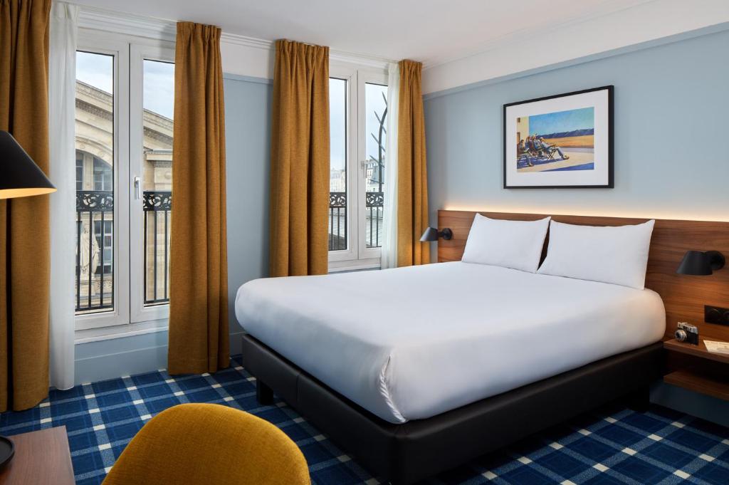 um quarto de hotel com uma cama e uma cadeira em Timhotel Paris du Gare du Nord em Paris
