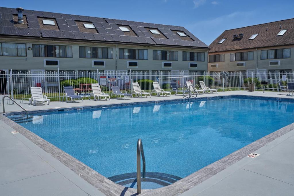 a large swimming pool with chairs and a building at Admiralty Inn & Suites - a Red Collection Hotel in Falmouth