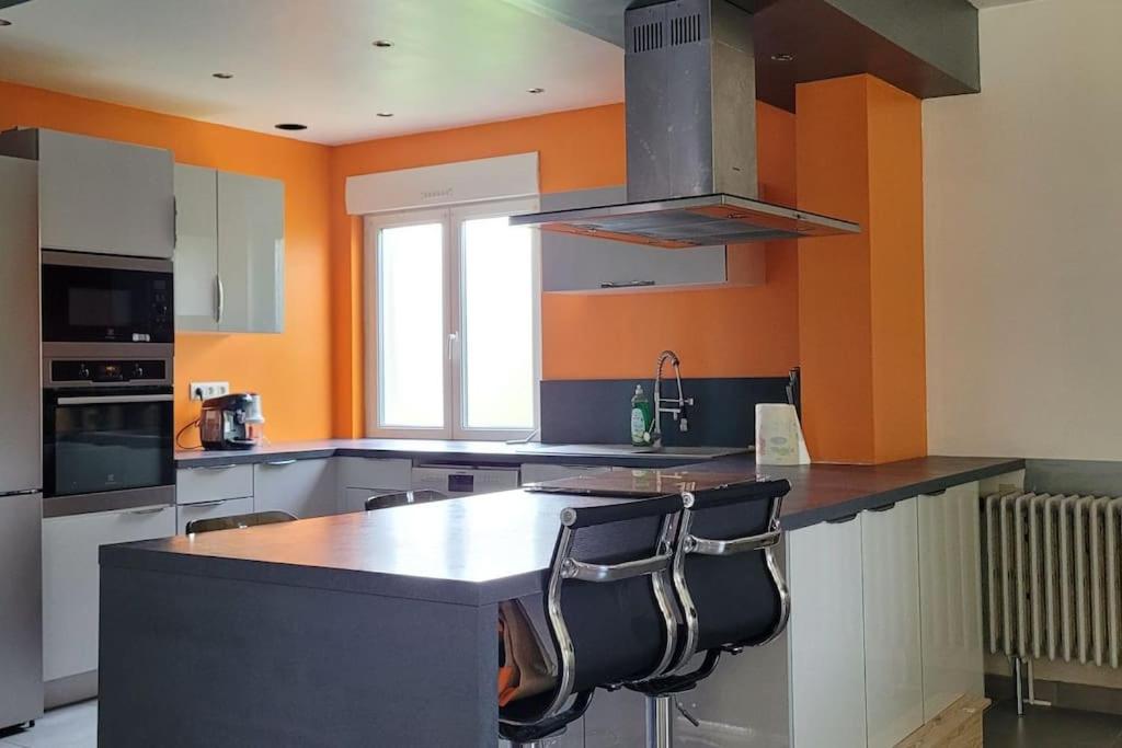 une cuisine avec un îlot avec deux chaises dedans dans l'établissement Maison spacieuse, à Quessigny