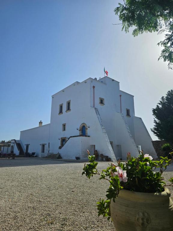 a white building with a staircase and flowers in a pot at Antica Masseria Torre Mozza in Torre Santa Susanna
