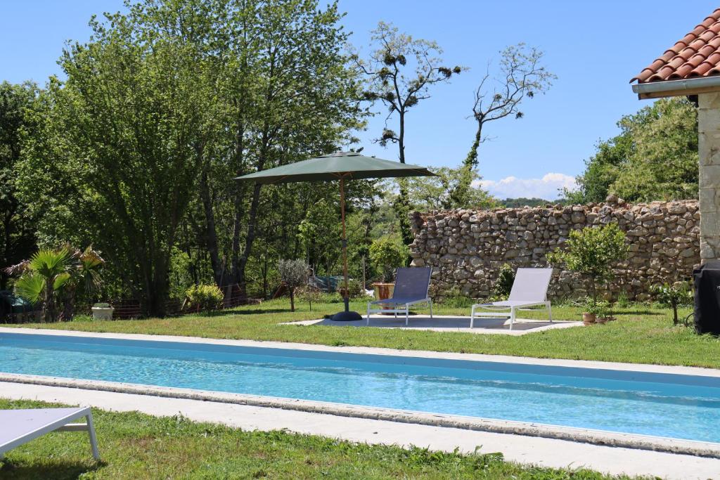 a swimming pool with two chairs and an umbrella at Ferme du Peyronin in Heugas