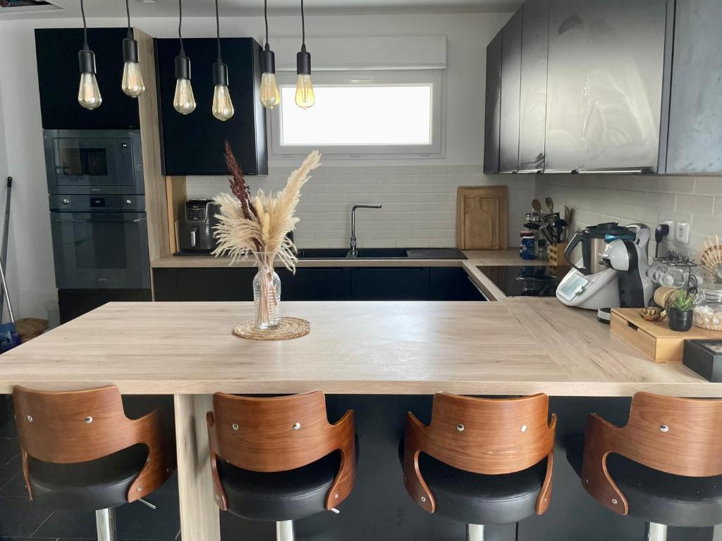 Una cocina con una mesa de madera y algunas sillas. en Maison JO 2024, en Villepinte