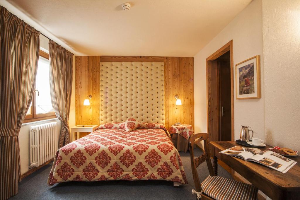 a bedroom with a bed and a desk and a table with a desk at Hotel Ruitor in Arvier