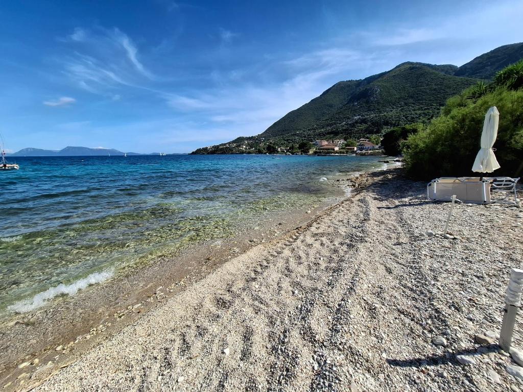 a beach with two chairs and the water at Lefkada Eli's amazing beach house in Nikiana