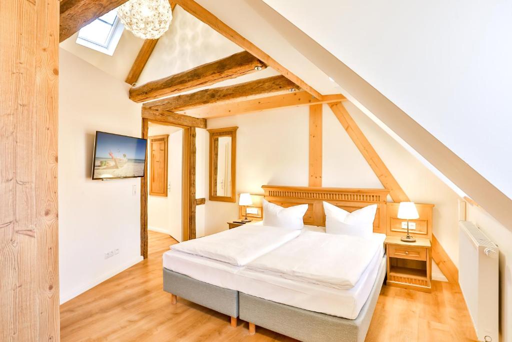 sypialnia z białym łóżkiem na poddaszu w obiekcie Aparthotel an Sankt Marien w mieście Stralsund