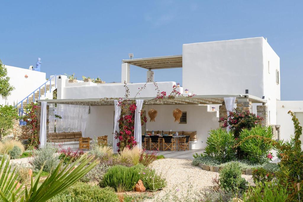 Villa Paralía - Best seaside في Agia Irini Paros: منزل أبيض وبه زهور في الفناء