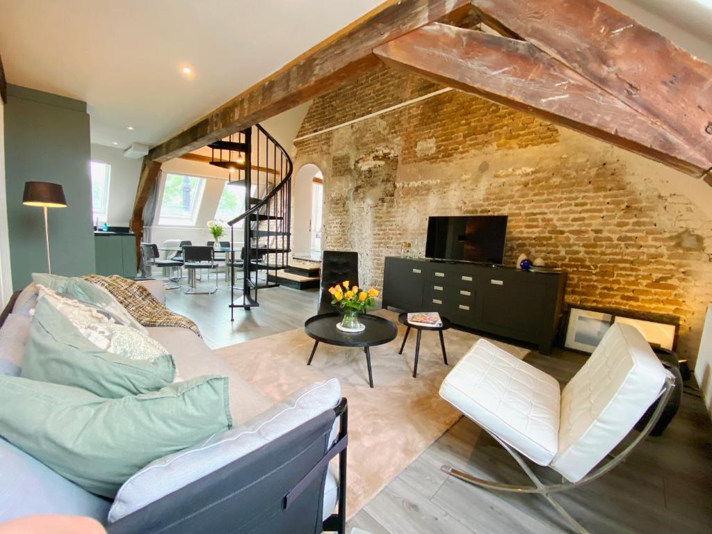een woonkamer met een bank en een bakstenen muur bij Luxe en ruim appartement in Rijksmonument in Vianen