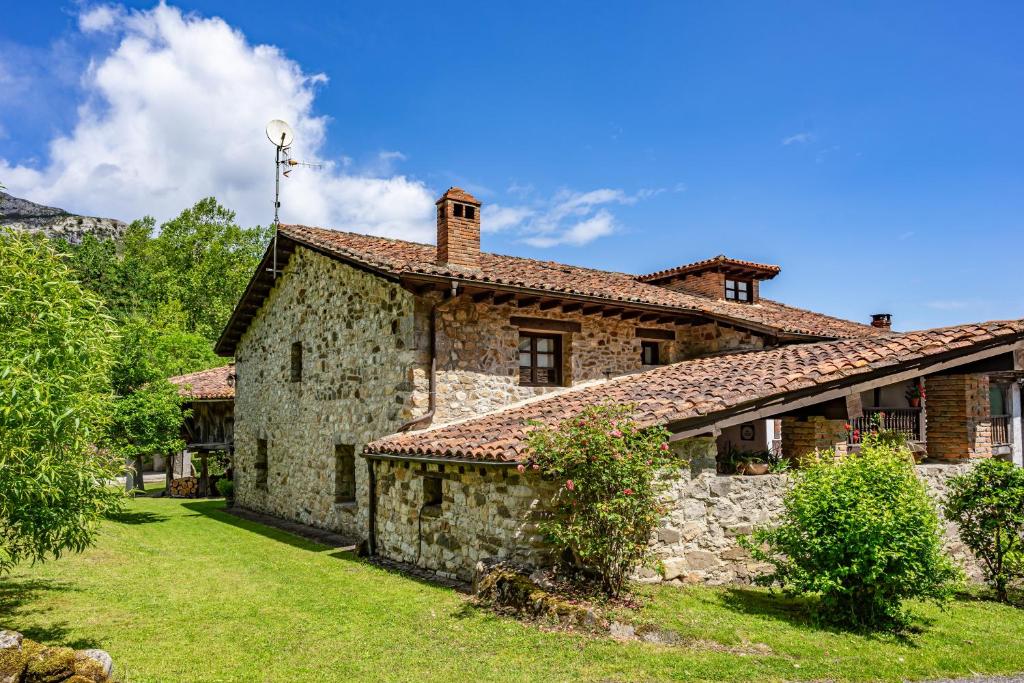 an old stone house with a grass yard at Casa De Aldea La Venta Los Probes in Llanes