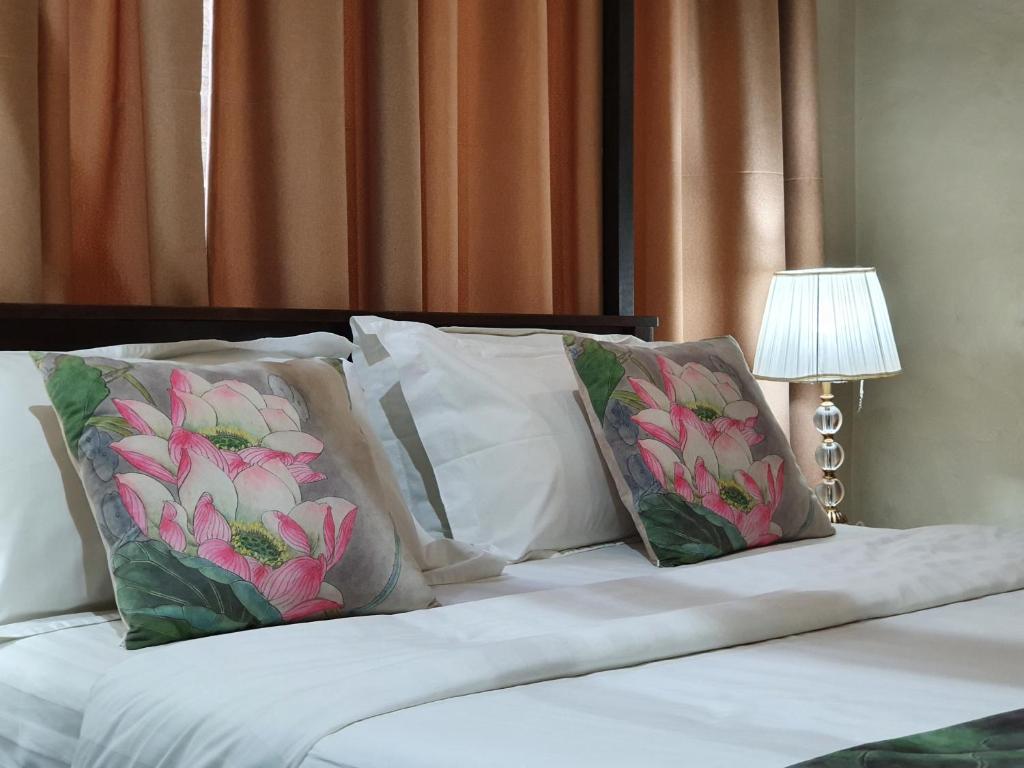 łóżko z 3 poduszkami i lampą w obiekcie Lotus by Serendib w mieście Blantyre