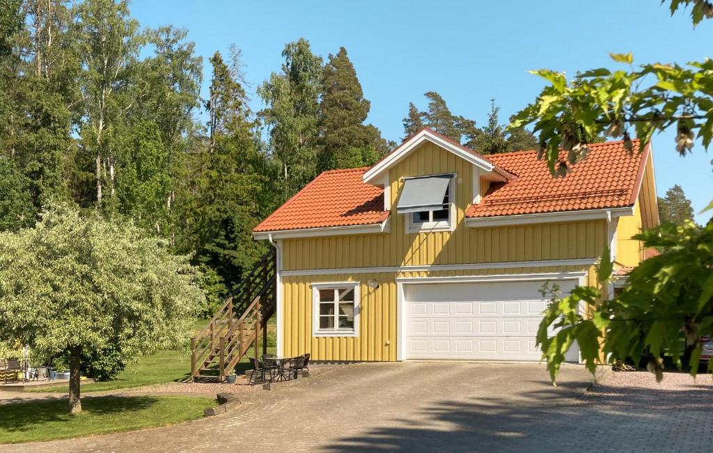 una casa amarilla con garaje blanco en Gorgeous Apartment In Hammar With Kitchen, en Hammarö