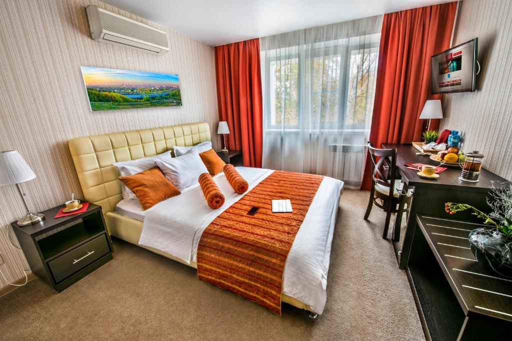 a bedroom with a bed with orange pillows and a desk at City Hotel Novosibirsk in Novosibirsk