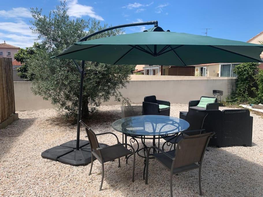 une table et des chaises avec un parasol vert dans l'établissement L étoile de mer logement 2, à Sainte-Marie-la-Mer