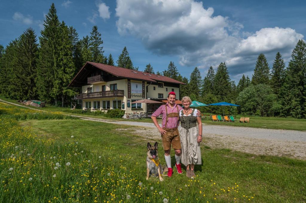 duas mulheres e um cão em frente a uma casa em Pension Arberwald em Bayerisch Eisenstein