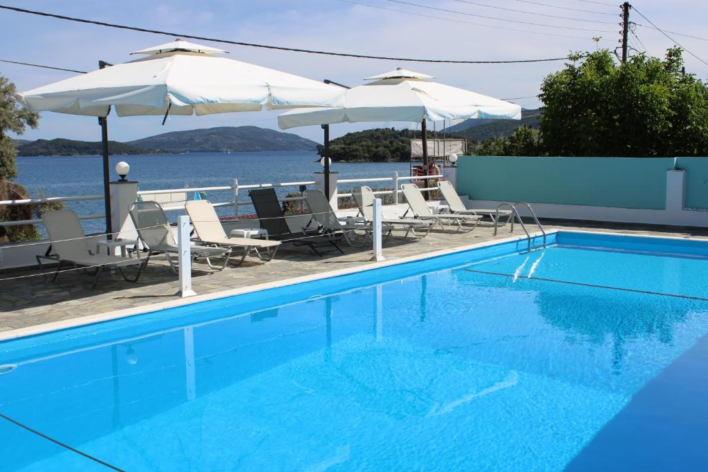 a swimming pool with chairs and umbrellas at Tropicana Inn in Nydri