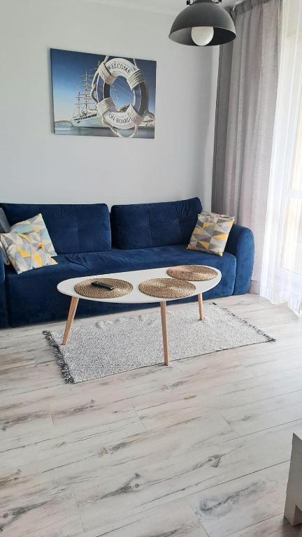 a living room with a blue couch and two tables at Aurora Apartament Gardenia in Międzywodzie