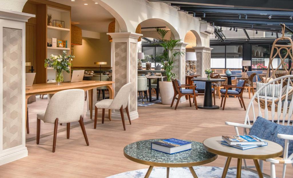 un'area salotto con tavoli e sedie in un ristorante di Hôtel Arcanse by Inwood Hotels ad Arcachon