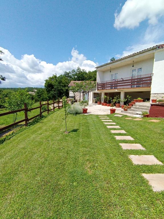 a house with a grassy yard next to a fence at B&B "Retro Gusto " in Pićan