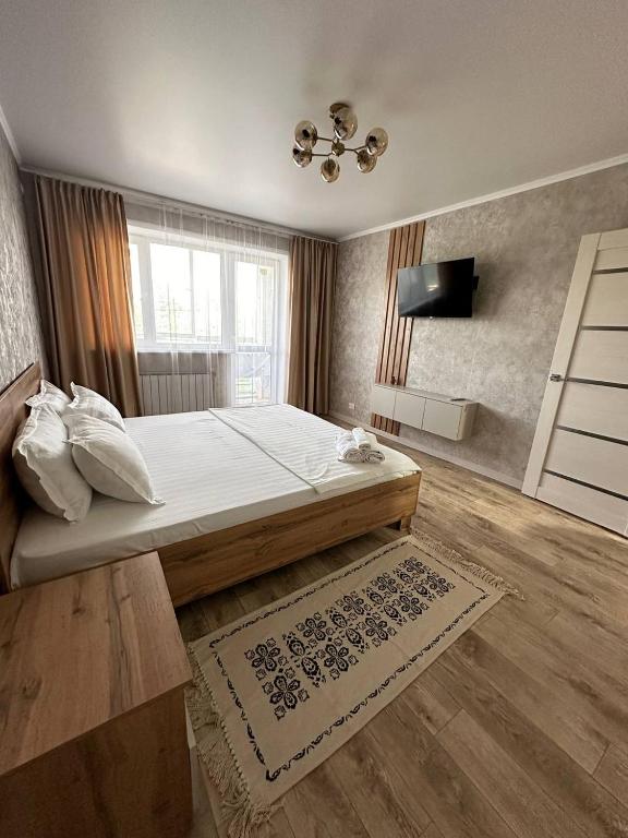 1 dormitorio con 1 cama grande y TV en Уютная квартира недалеко от Аэропорта, en Kostanái