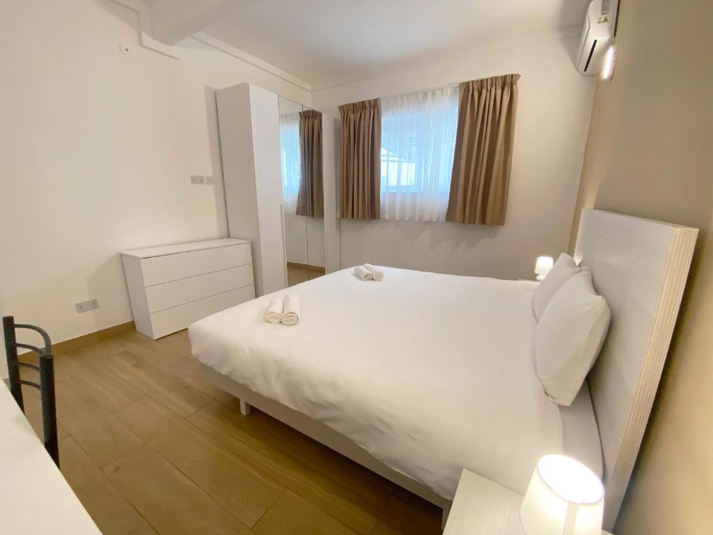 a bedroom with a white bed and a mirror at Miami Apartments in St. Julianʼs