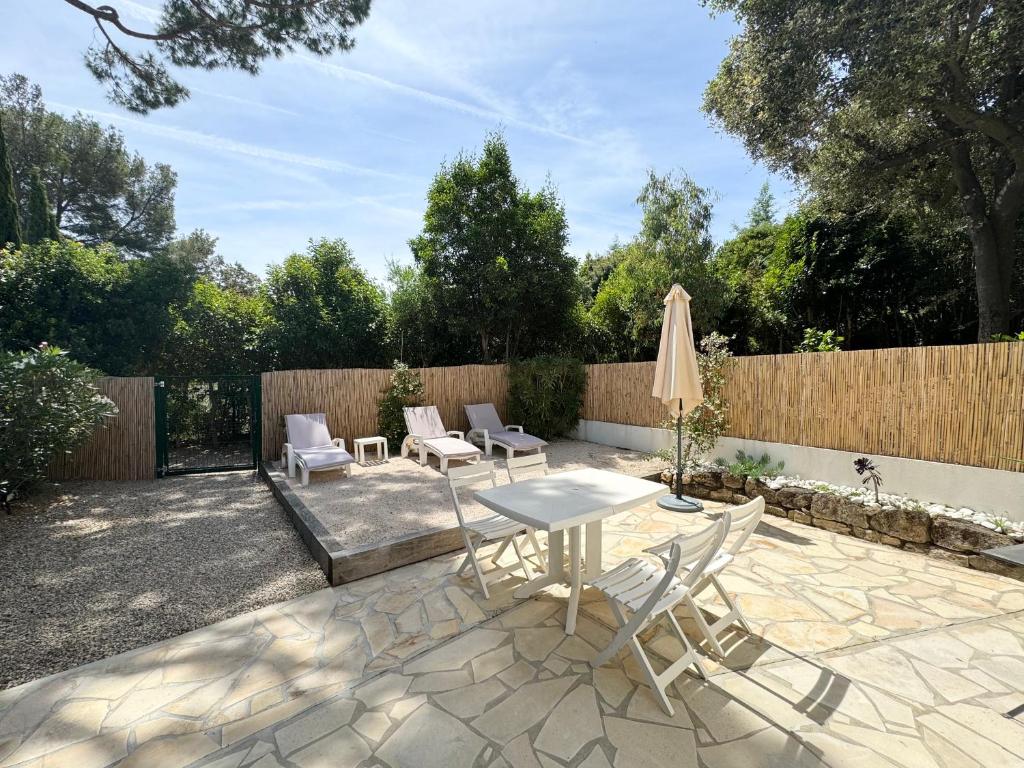 un patio con mesa, sillas y sombrilla en Appartement 1ch avec terrasse et jardinet à 400m de la plage, en Cavalaire-sur-Mer