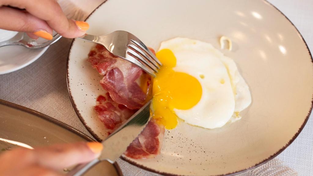 a person eating a plate with an egg and bacon at Palazzo Zacà in Gallipoli