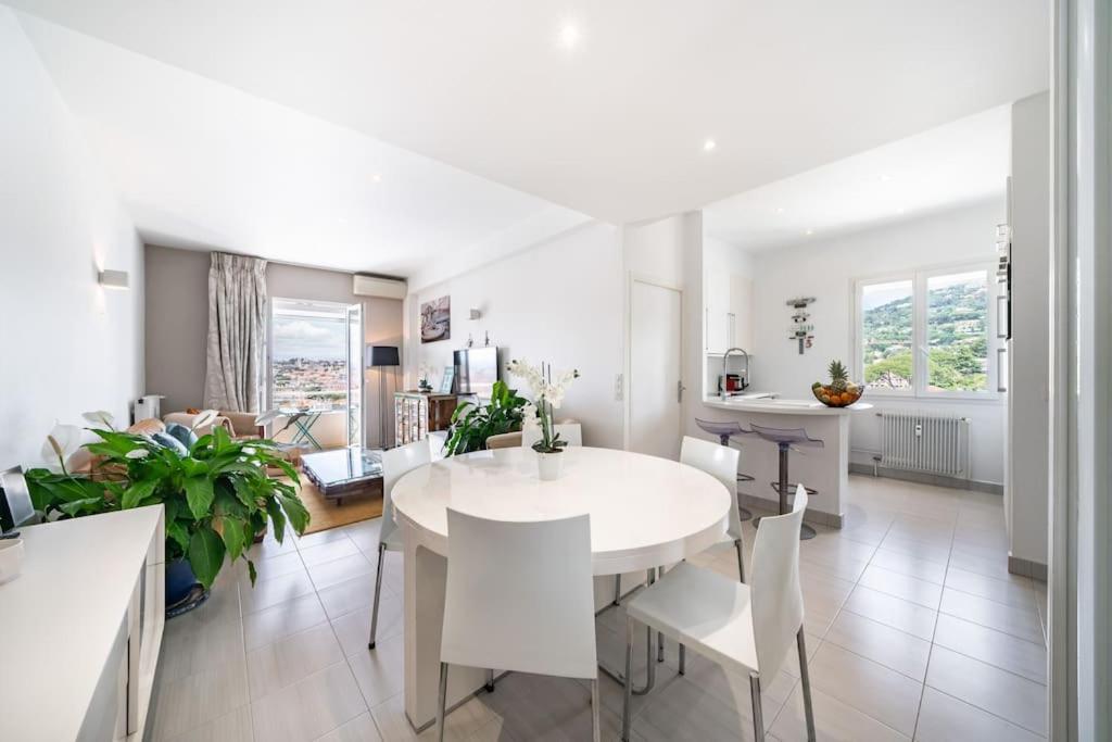 une cuisine et un salon avec une table et des chaises blanches dans l'établissement Superbe appartement vue mer Gallia, à Cannes