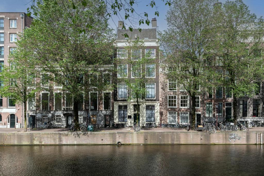 un bâtiment avec des arbres en face d'une rivière dans l'établissement The Sixteen, à Amsterdam